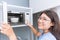 Girl teen smiling reheat food by using microwave oven with glass ceramic bowl
