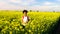 Girl teenager female young woman hiking with red backpack and bottle of water in field of yellow flowers