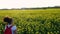 Girl teenager female young woman hiking with red backpack and bottle of water in field of yellow flowers