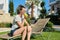 Girl teenager with green apple, resting sitting on sun lounger in garden