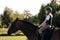 Girl teenager jockey sits on a brown horse in nature.