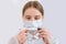 Girl teenager, medical mask covers her face, holds digital electronic thermometer hand, checks temperature, symptoms