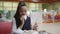 Girl teenager in a school uniform sitting at a table in the school cafeteria eating cakes and drinking tea.