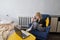 Girl teenager sits in chair near wall behind yellow table and concentrated looking at laptop screen