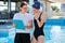 Girl teenager swimmer in sports swimsuit cap with woman trainer near outdoor pool