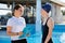 Girl teenager swimmer in sports swimsuit cap with woman trainer near outdoor pool