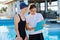 Girl teenager swimmer in sports swimsuit cap with woman trainer near outdoor pool