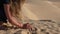 Girl teenager taking and pouring sand from hand in hot Sahara desert. Closeup hand