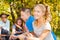 Girl and teens sit on campsite with sausages