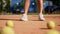 A girl tennis player stands on the sports field and practices hitting the ball with a racket on the ground. The training