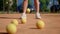 A girl tennis player stands on the sports field and practices hitting the ball with a racket on the ground. The training