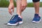 Girl ties up shoelaces in sneakers on road while jogging, legs and sneakers