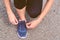 Girl ties up shoelaces in sneakers on road while jogging, legs and sneakers, toned image