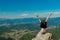 The girl at the top of the mountain raised her hands up. Wide summer mountain view at sunrise and distant mountain range covered.