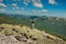 The girl at the top of the mountain raised her hands up. Wide summer mountain view at sunrise and distant mountain range covered.