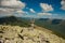 The girl at the top of the mountain raised her hands up. Wide summer mountain view at sunrise and distant mountain range covered.