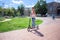 A girl in torn fashionable jeans is riding a scooter in a summer park