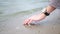 The girl touches the sand on the river with her fingers. Close-up shot of a woman\\\'s hand on a background of sand