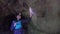 Girl tourist with a backpack and a flashlight on his forehead inside a dark cave examines the stones