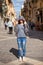 Girl tourist in jeans with glasses and a hood in the form of a cobra stands alone in the middle of narrow streets