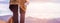 Girl tourist stands on hill with bottle of drinking water in hand. Legs of traveler and backpack close-up