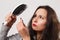 A girl with tousled shaggy hair holds a comb in her hands