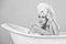 Girl with towel turban sitting in white bathtub. Black white.