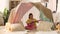 Girl with toy guitar playing in kids tent at home