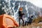 Girl with track sticks and a guy with binoculars on a halt near a tourist tent in the mountains examine the surroundings against t