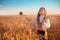 Girl with traditional Bulgarian folklore costume at the agricultural wheat field during harvest time with industrial combine