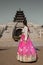 Girl in traditional pink skirt Korean costume hanbok standing in front of an ancient five stores religious pagoda in Seoul South