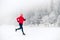 Girl trail running on snow in winter mountains