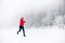 Girl trail running on snow in winter mountains