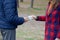 Girl transfers euro bills to the hands of a young guy in forest. Concept of robbery or illegal deal transaction