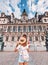 Girl traveler with a cute backpack enjoys the view of the stunning Gothic architecture of the old town Hall in Paris.