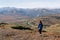 Girl traveler on the edge of the cliff looking at the plain and mountains, green and orange hills