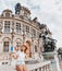 Girl traveler with a french flag enjoys the view of the stunning Gothic architecture of the old town Hall in Paris.