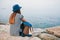 Girl traveler in a hat with a backpack next to the sea looking into the distance. Travel, rest, hiking, freedom.