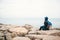 Girl traveler in a hat with a backpack next to the sea looking into the distance. Travel, rest, hiking, freedom.