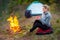 Girl traveler resting with a cup of tea by the fire and tents in