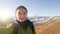 A girl traveler takes a selfie on the background of mount Elbrus. Warm coat. Autumn trip to Russia. The glare of the sun. Bright