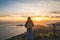 Girl traveler watching a beautiful sunset over the Pacific Ocean on top of a hill