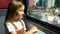The girl travels by train and looks out the window