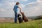 The girl treats two dogs a treat. Doberman and border collie dogs are sitting on a hill. Horizontal orientation.