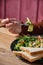 Girl tries a salad with tomatoes, feta, lettuce, toasts on a table, on