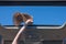 Girl trowing away her straw hat out from open hatch of a vehicle.