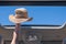 Girl trowing away her straw hat out from open hatch of a vehicle.