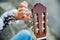 The girl tunes the guitar. Female hands close-up twist clips on the guitar. Learning music