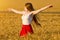 Girl turned her arms outstretched in a wheat field