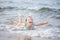 Girl in a turquoise bathing suit in the sea, happy children swimming in the sea, waves and splashes from swimming in the sea